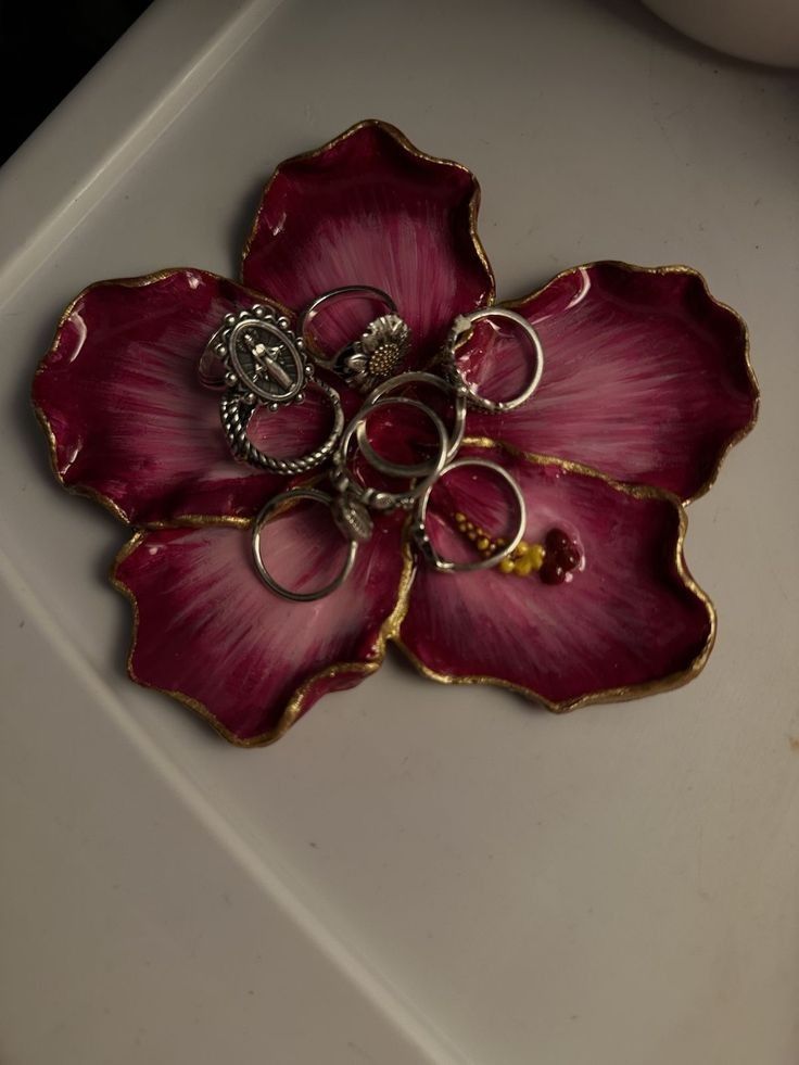 43f25719-28d1-4e22-b62d-d163039aedd2 Colorful flower-shaped dish holding various silver rings. | Sky Rye Design Colorful flower-shaped dish holding various silver rings.