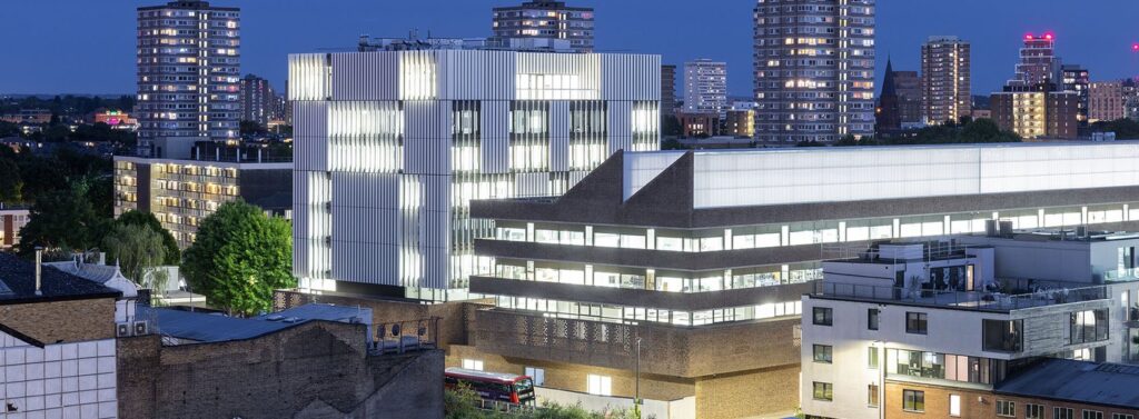 472_RCA_22-05_HdM_3199b1cfbdf3fill-1440x530 Modern cityscape at dusk featuring illuminated buildings and high-rises against a twilight sky. | Sky Rye Design Modern cityscape at dusk featuring illuminated buildings and high-rises against a twilight sky.