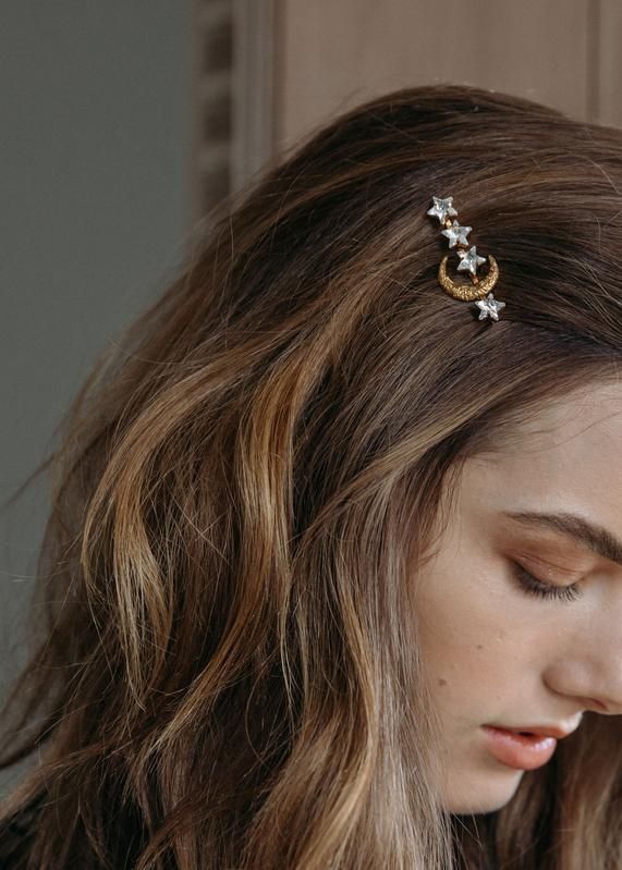 Close-up of woman with brown hair wearing a star and crescent moon hair clip, side view, elegant hairstyle accessory.