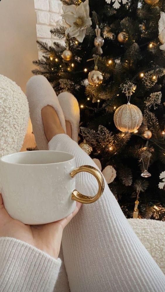 4cd08873-d1d2-4e1a-a76d-c48404e96464 Cozy winter vibes: person holds mug near decorated Christmas tree, wearing comfy slippers. | Sky Rye Design Cozy winter vibes: person holds mug near decorated Christmas tree, wearing comfy slippers.