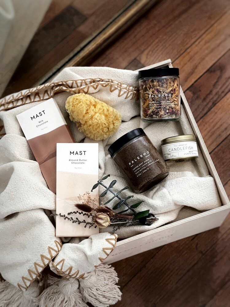 4eb7929a20385df2269d11c9b4780e81 Gift box with chocolate, candle, bath products, and dried flowers on a cozy blanket. | Sky Rye Design Gift box with chocolate, candle, bath products, and dried flowers on a cozy blanket.