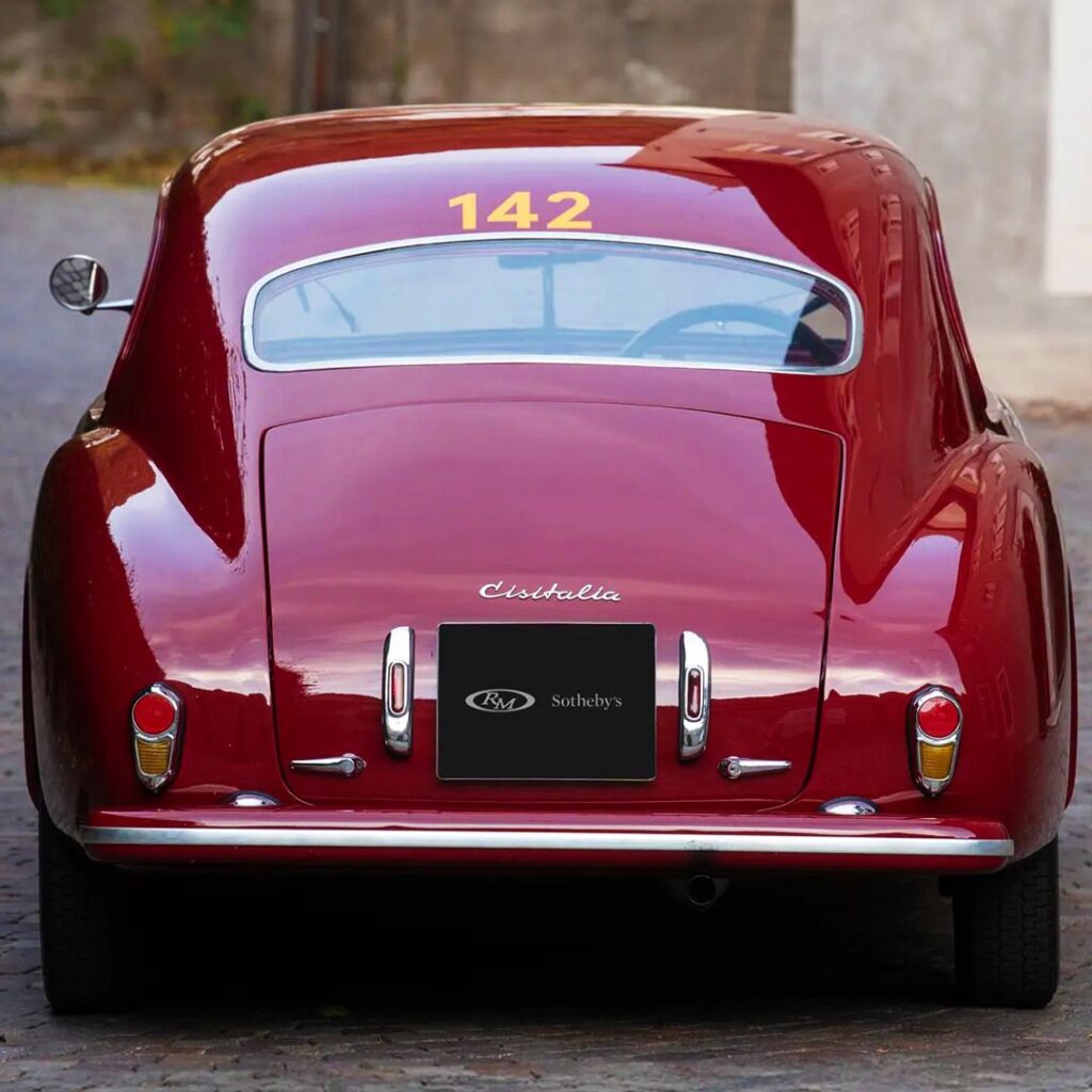 Rear view of a classic red sports car with number 142 displayed, showcasing vintage elegance.