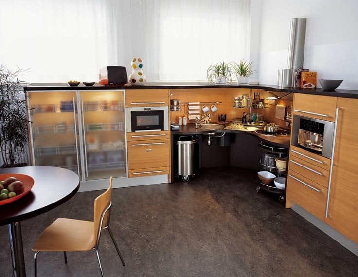 Modern kitchen with wooden cabinets, built-in appliances, and a round table, featuring efficient storage solutions.