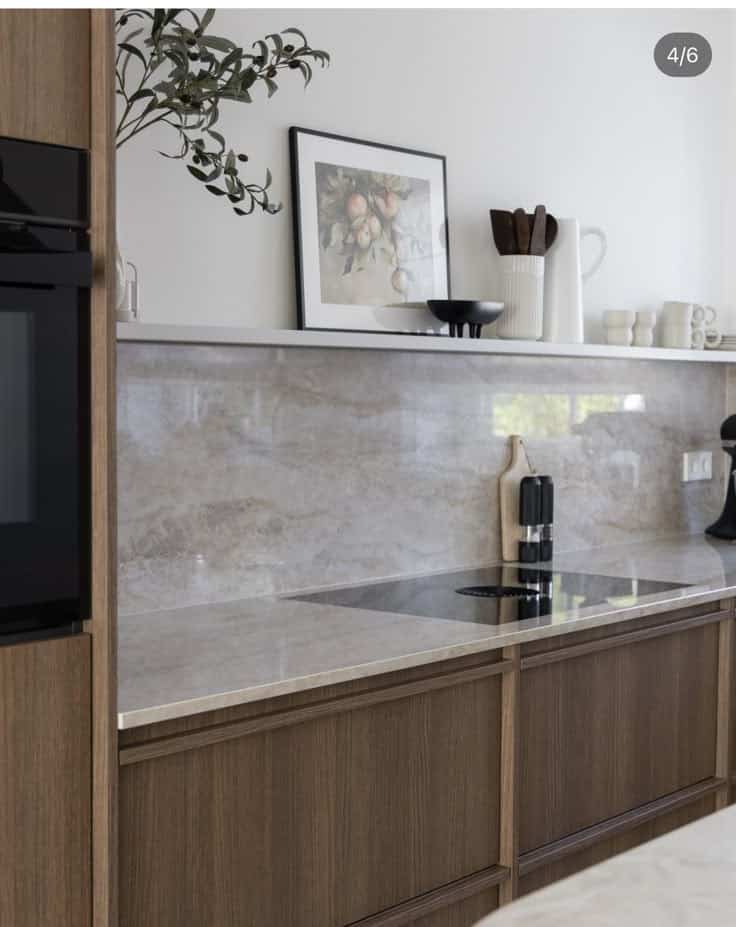 Screenshot Modern kitchen with wooden cabinets, marble backsplash, and stylish decor, featuring art and kitchen essentials. | Sky Rye Design Modern kitchen with wooden cabinets, marble backsplash, and stylish decor, featuring art and kitchen essentials.