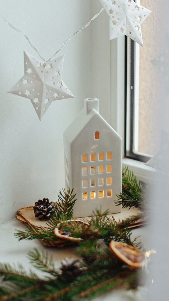 _ 5 Ceramic house with candlelight, star lights, and pine decor creating a cozy winter ambiance by the window. | Sky Rye Design Ceramic house with candlelight, star lights, and pine decor creating a cozy winter ambiance by the window.