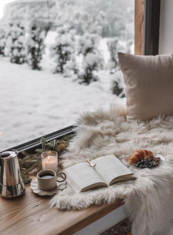 5440a10b-758b-4e76-82ab-10ad9e12f05f Cozy winter window nook with a book, candle, coffee, croissant, and snow-covered view. Perfect for relaxing moments. | Sky Rye Design Cozy winter window nook with a book, candle, coffee, croissant, and snow-covered view. Perfect for relaxing moments.