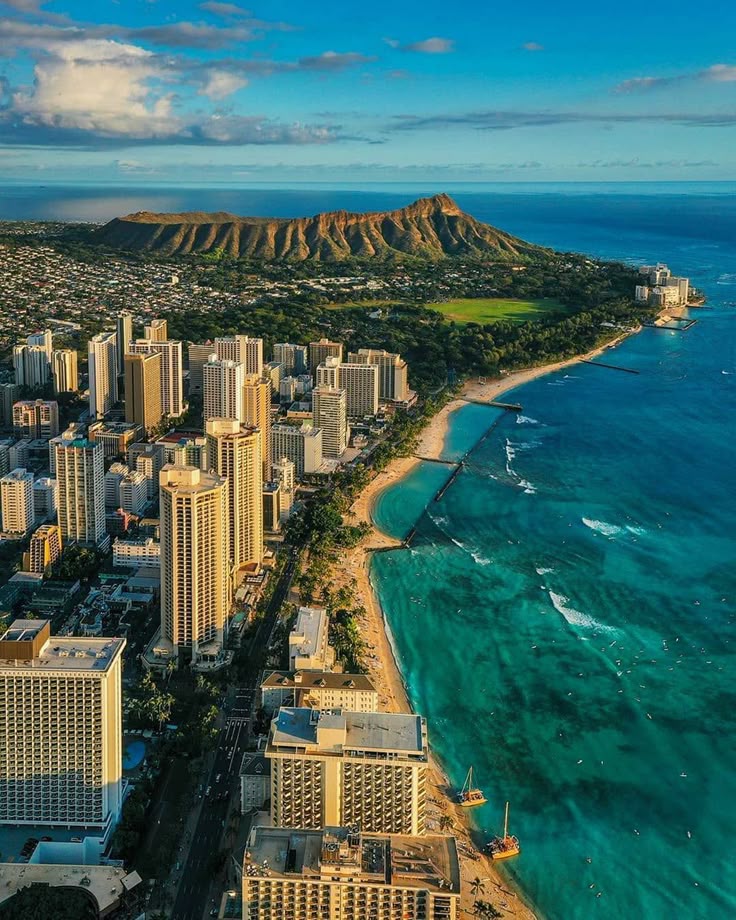 Aerial view of Waikiki Beach and Diamond Head, Honolulu, with turquoise ocean and city skyline under a clear blue sky.