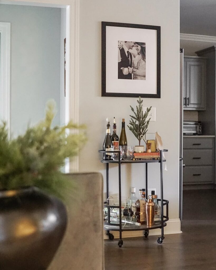 563cfeeb25d6ae156e275feaa5013fb8 Home bar cart with bottles and glasses beneath a framed photo, next to a kitchen view. | Sky Rye Design Home bar cart with bottles and glasses beneath a framed photo, next to a kitchen view.
