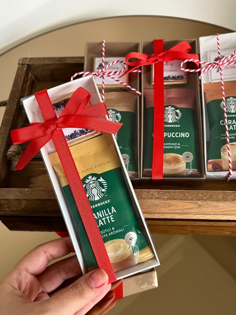 Gift box with Starbucks Vanilla Latte and Cappuccino packs, tied with red ribbon in a wooden tray.