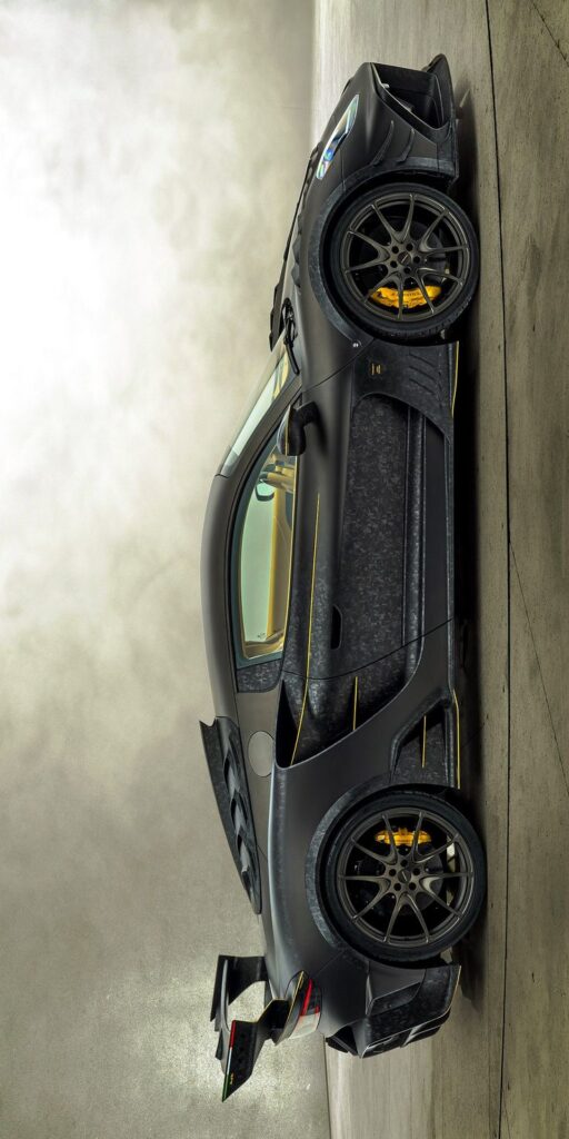 Sleek black sports car with yellow accents, side view in a garage setting.