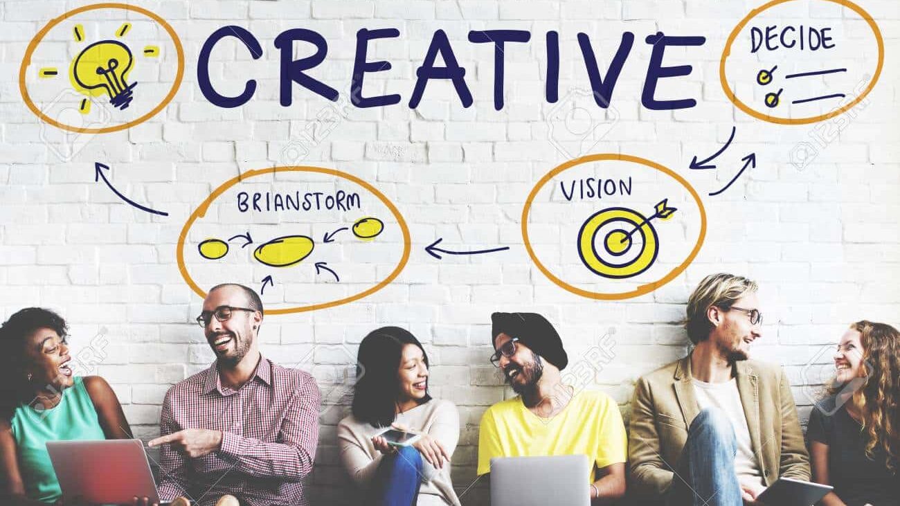 Creative Creativity Innovation Design Vision Concept Creative team brainstorming with laptops, surrounded by words like research, decide, vision on a white brick wall background. | Sky Rye Design Creative team brainstorming with laptops, surrounded by words like research, decide, vision on a white brick wall background.