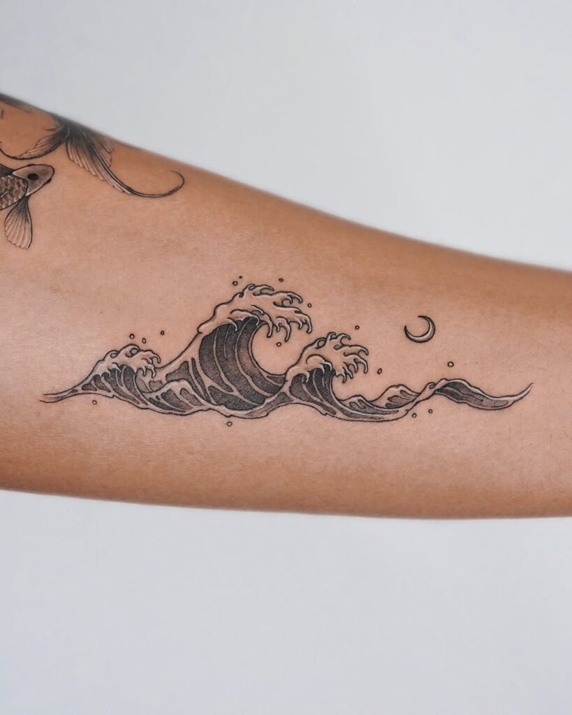 Minimalist wave tattoo with crescent moon on forearm, showing ocean-inspired design art.