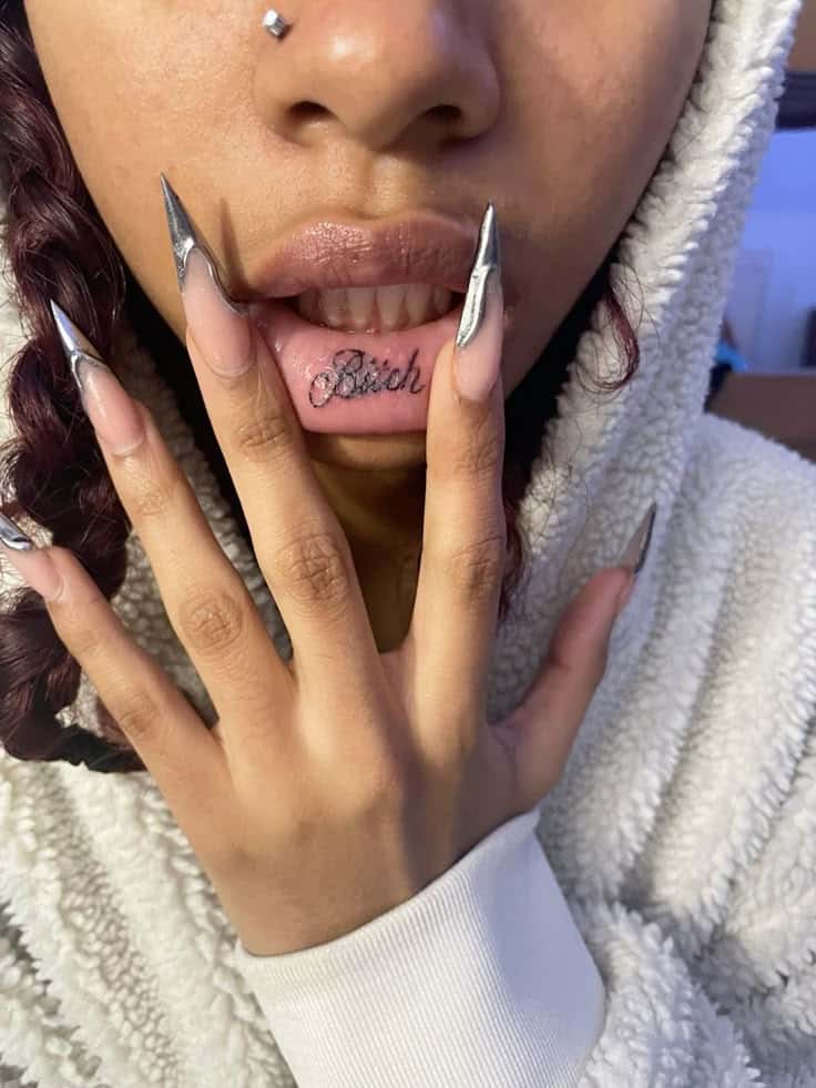5bc22f299b7161f5f1107d96f65c7306 Person displaying lip tattoo and silver nails while wearing a cozy hooded sweater. | Sky Rye Design Person displaying lip tattoo and silver nails while wearing a cozy hooded sweater.