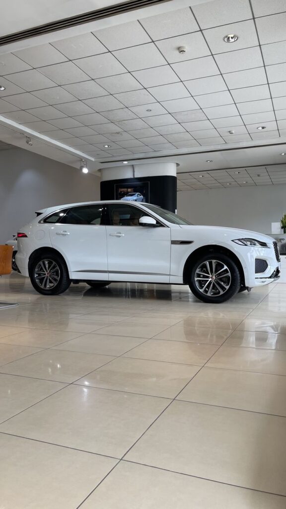 Sleek white luxury SUV in a car showroom with polished tile flooring and modern ceiling design.