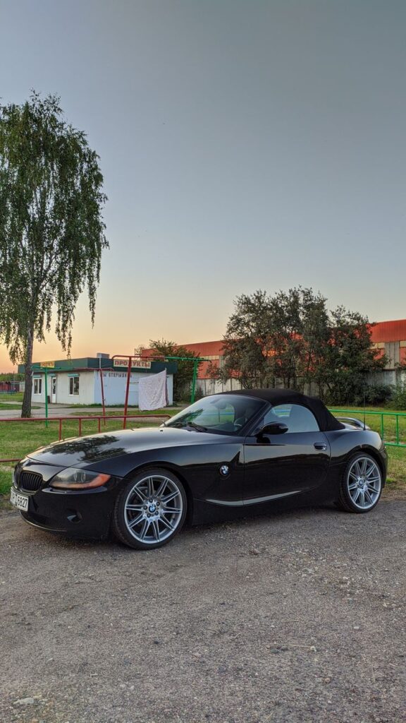 Sleek black convertible car parked outdoors at sunset, highlighting its modern design against a scenic backdrop.