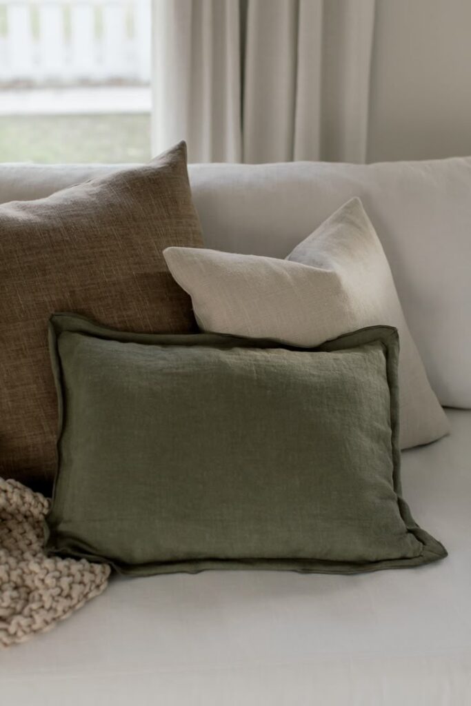 5e1d0628de156d35c3b29f62fcb3f7bc Cozy sofa with green, brown, and beige pillows and a knit throw, creating a warm and inviting living room atmosphere. | Sky Rye Design Cozy sofa with green, brown, and beige pillows and a knit throw, creating a warm and inviting living room atmosphere.