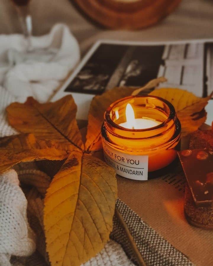 _ 6 Cozy autumn scene with a lit candle in a jar, yellow leaves, and warm textures for a relaxing atmosphere. | Sky Rye Design Cozy autumn scene with a lit candle in a jar, yellow leaves, and warm textures for a relaxing atmosphere.