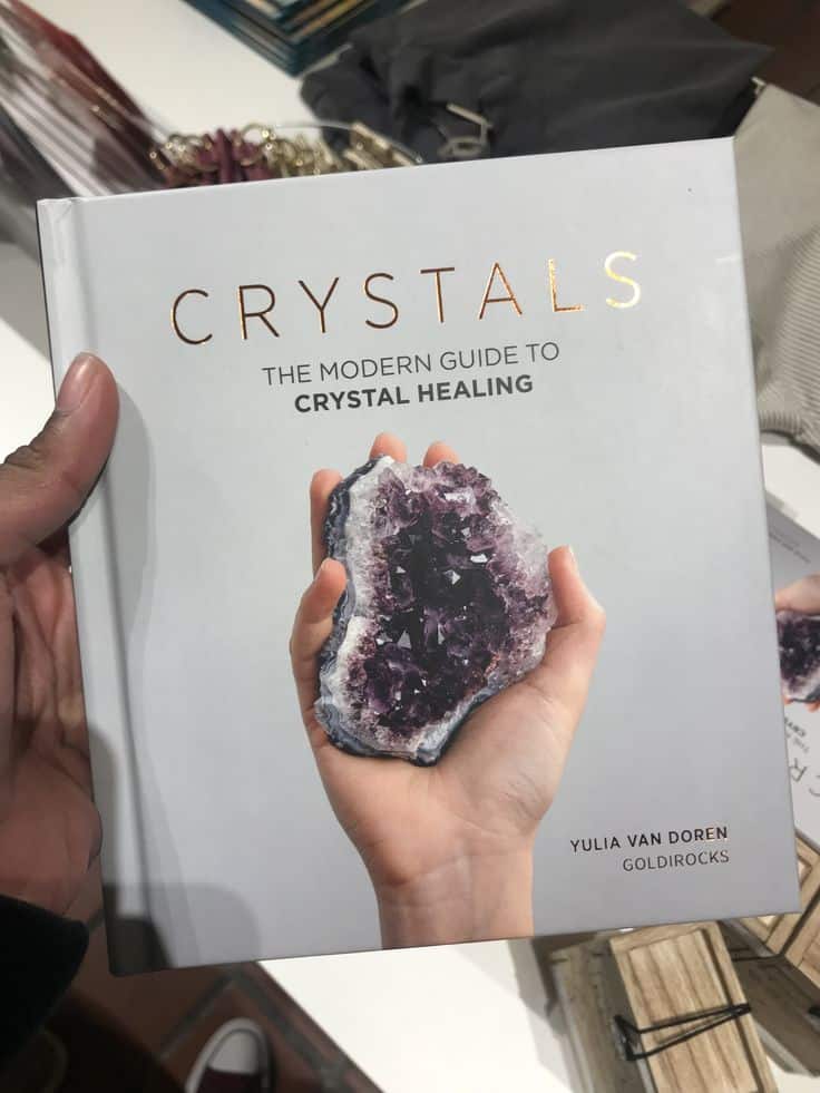 Cover of Crystals: The Modern Guide to Crystal Healing by Yulia Van Doren featuring a hand holding a purple crystal.