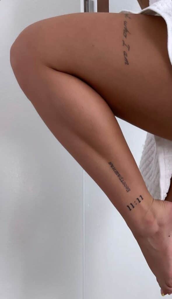 _ 6 Close-up of a leg displaying multiple tattoos, including 11:11 and cursive script, against a neutral background. | Sky Rye Design Close-up of a leg displaying multiple tattoos, including 11:11 and cursive script, against a neutral background.