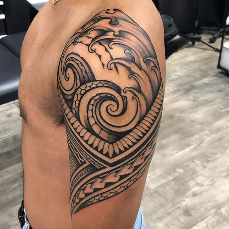 Ornate tribal-style tattoo design on a man's upper arm, featuring bold swirling patterns and intricate details.