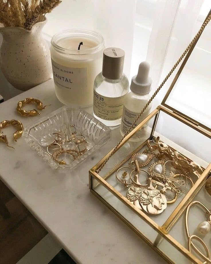 6 maneiras estilosas de combinar acessórios dourados Elegant gold jewelry, skincare products, and a scented candle on a marble table for a chic, minimalist decor. | Sky Rye Design Elegant gold jewelry, skincare products, and a scented candle on a marble table for a chic, minimalist decor.