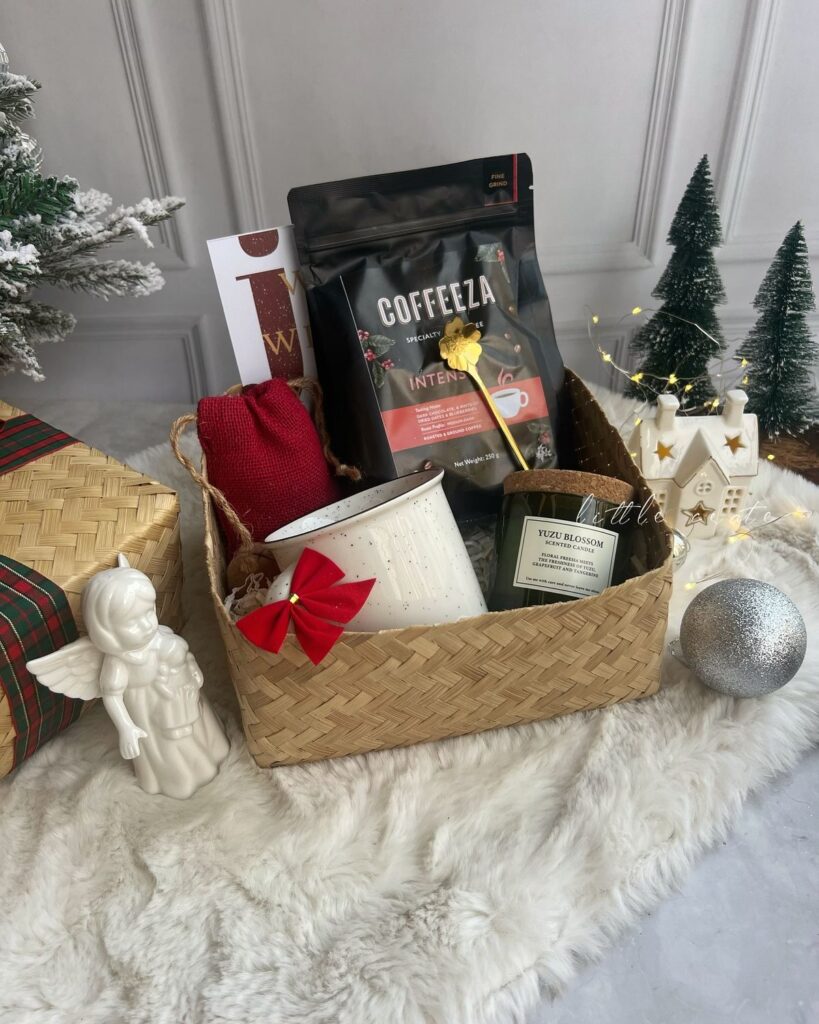 672591c884323ec1713369b4bfa4ff9e Festive gift basket with coffee, candle, and mug, surrounded by holiday decor and fairy lights on a cozy fur surface. | Sky Rye Design Festive gift basket with coffee, candle, and mug, surrounded by holiday decor and fairy lights on a cozy fur surface.