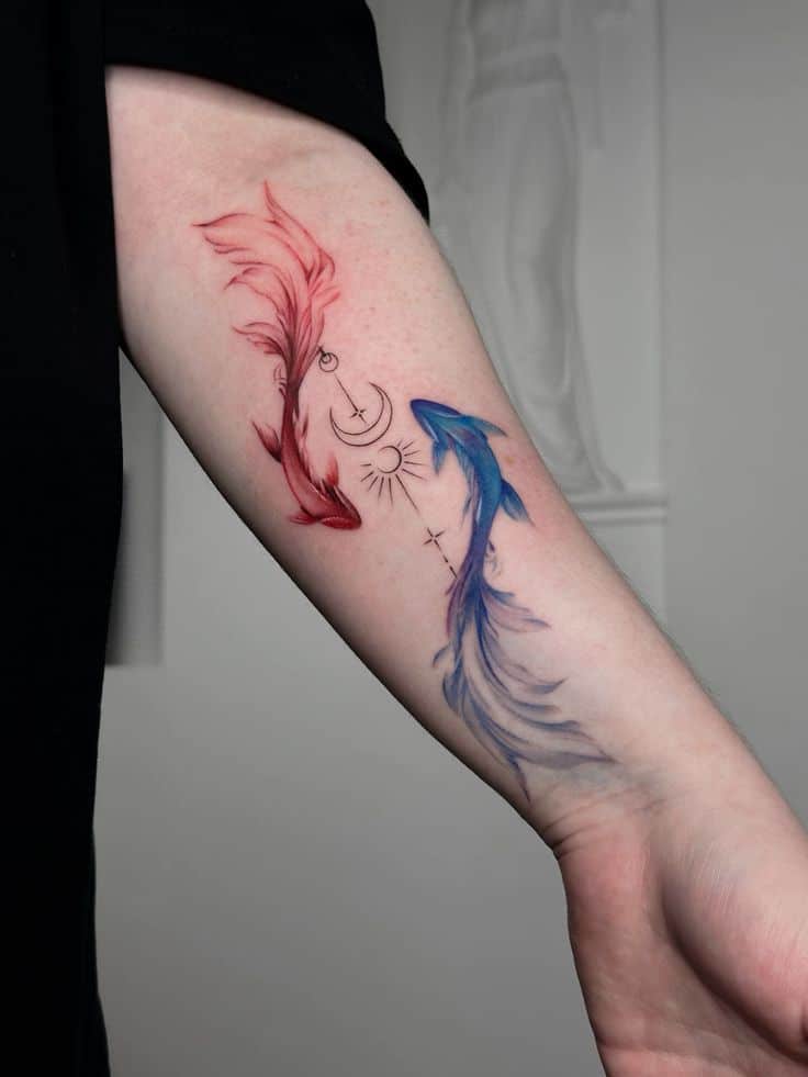 Colorful koi fish tattoo with red and blue designs, featuring moon and sun symbols on a person's forearm.