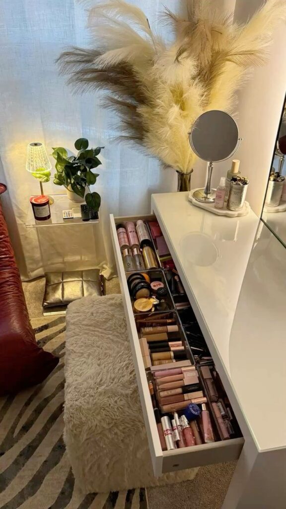 6e4fb4e5-e2fe-4253-84b2-f1391f22e971 Vanity table with open drawer full of makeup products, mirror, perfume, and decorative plants. | Sky Rye Design Vanity table with open drawer full of makeup products, mirror, perfume, and decorative plants.