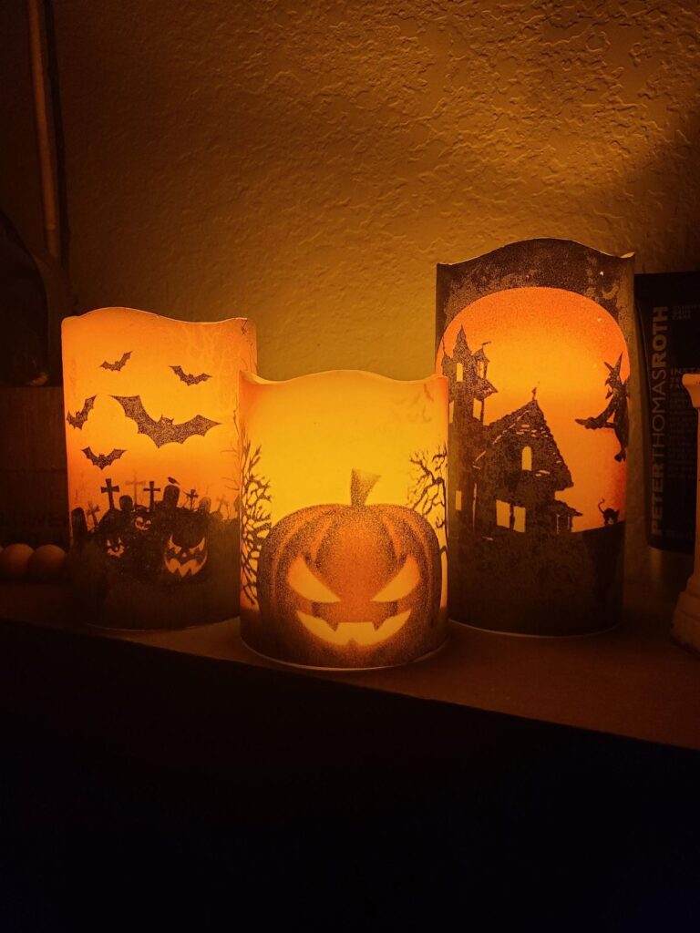 6ebbd80a8417d8d16dd74e2da4f84443 Halloween-themed candles with glowing jack-o'-lantern, bats, and haunted house designs on a dimly lit shelf. | Sky Rye Design Halloween-themed candles with glowing jack-o'-lantern, bats, and haunted house designs on a dimly lit shelf.