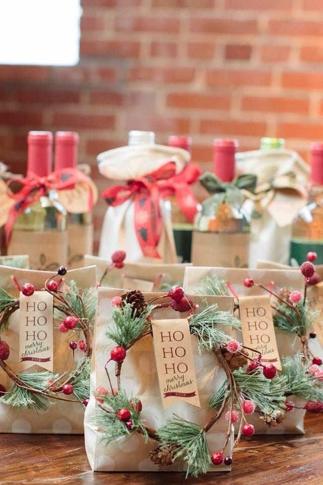 _ 7 Festive gift bags and decorated wine bottles with Christmas tags and greenery, set on wooden table with brick backdrop. | Sky Rye Design Festive gift bags and decorated wine bottles with Christmas tags and greenery, set on wooden table with brick backdrop.