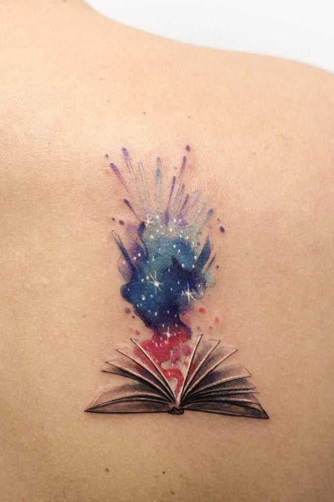 _ 7 Tattoo of an open book with colorful galaxy ink splashes on skin, symbolizing imagination and creativity. | Sky Rye Design Tattoo of an open book with colorful galaxy ink splashes on skin, symbolizing imagination and creativity.