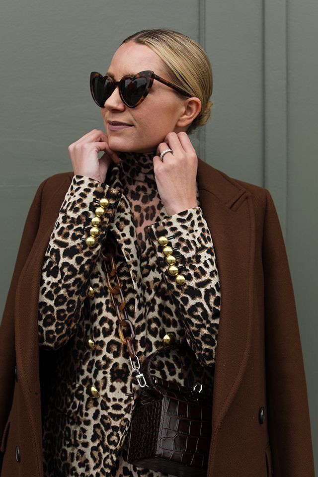 _ 7 Fashionable woman in leopard print top and brown coat, wearing heart-shaped sunglasses, with a small textured handbag. | Sky Rye Design Fashionable woman in leopard print top and brown coat, wearing heart-shaped sunglasses, with a small textured handbag.