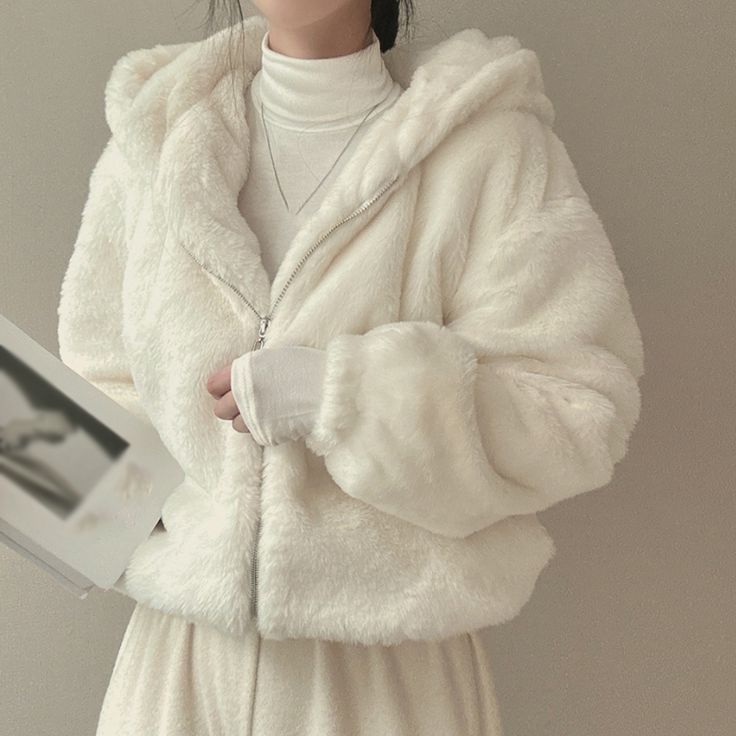Woman in a cozy white plush coat and turtleneck, holding a book, perfect for winter fashion inspiration.