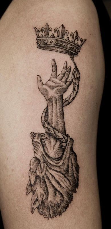 70+ Amazing Crown Tattoos Designs with Meanings Ideas and Celebrities - Body Art Guru Tattoo of an arm reaching for a crown, entwined by a snake, with a wolf head at the base. Black ink design. | Sky Rye Design Tattoo of an arm reaching for a crown, entwined by a snake, with a wolf head at the base. Black ink design.
