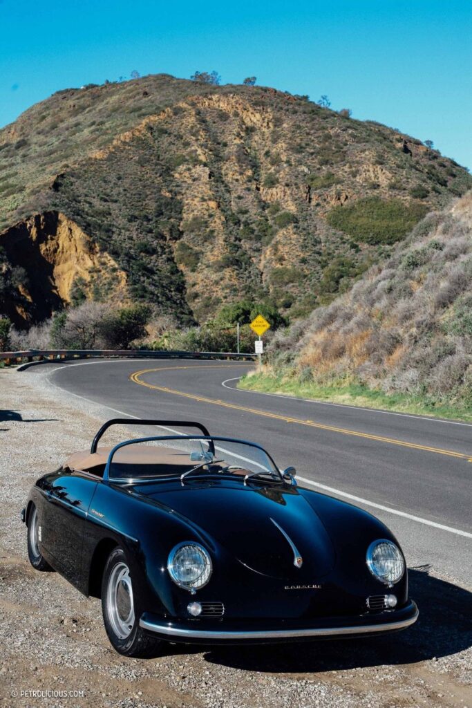 Classic black convertible on a scenic mountain road under a clear blue sky.