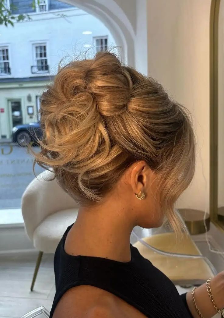 Elegant blonde updo hairstyle with curls, showcased in a stylish salon setting.