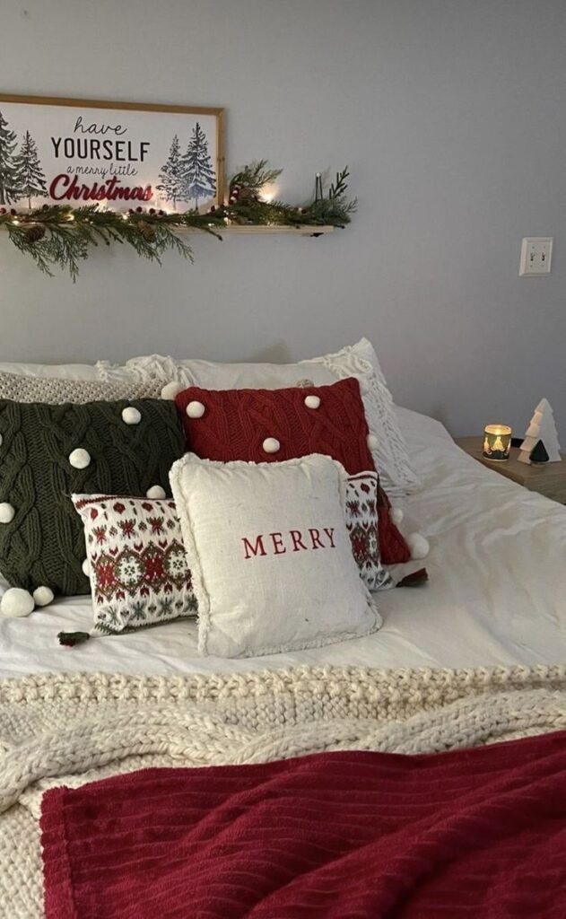 Cozy Christmas-themed bedroom with decorative pillows and festive garland on shelf.