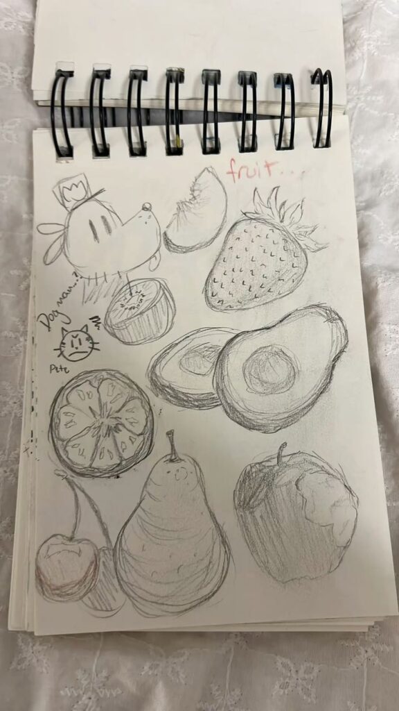 Sketchbook page with pencil drawings of various fruits and a cartoon dog character.