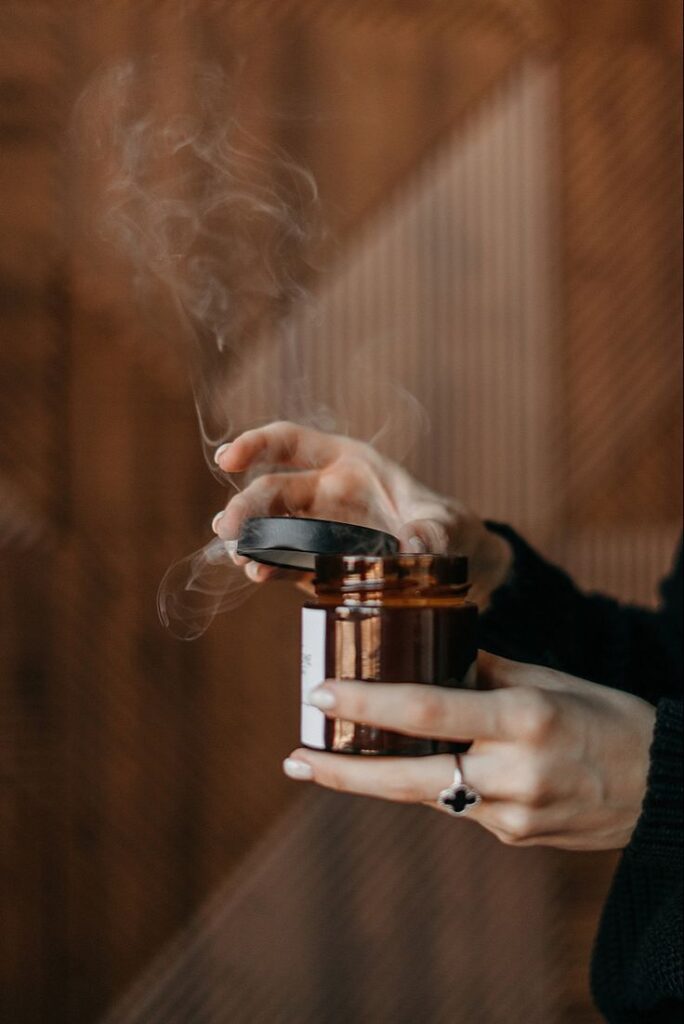 _ 8 Hands opening a steaming candle jar, warm ambiance, brown background. Perfect for spa or relaxation themes. | Sky Rye Design Hands opening a steaming candle jar, warm ambiance, brown background. Perfect for spa or relaxation themes.