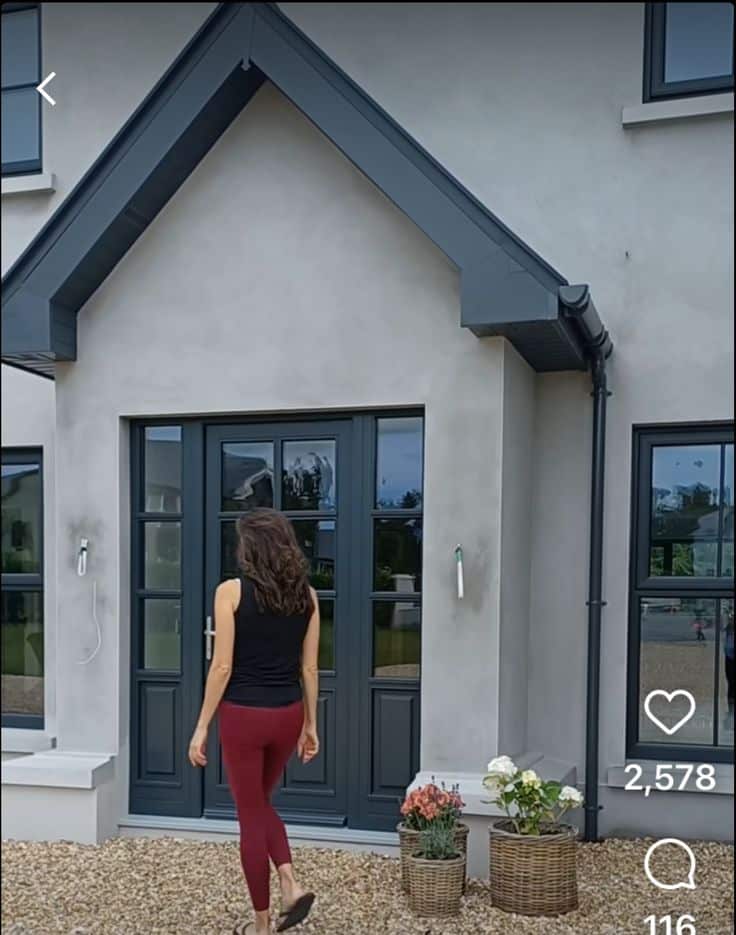 _ 8 Person walking towards a modern front door with plants in baskets on a gravel path. | Sky Rye Design Person walking towards a modern front door with plants in baskets on a gravel path.
