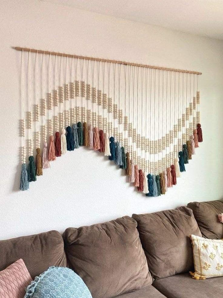 8186f9a3-9c15-4bda-b7b3-80cddae8f6b6 Colorful macramé wall hanging with tassels above brown couch, adding boho style to the living room decor. | Sky Rye Design Colorful macramé wall hanging with tassels above brown couch, adding boho style to the living room decor.