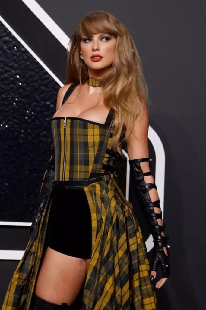 Stylish woman in yellow and black plaid dress with leather gloves poses confidently against a dark background.