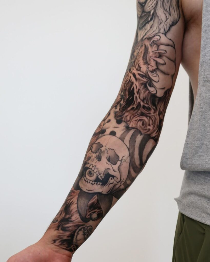 Detailed black and grey sleeve tattoo featuring a skull, lion, and intricate designs on a person's arm.