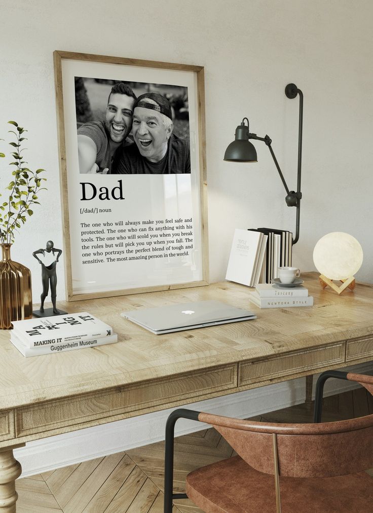 Modern home office with framed dad-themed art on desk, laptop, books, and stylish decor elements. Warm, inviting design.