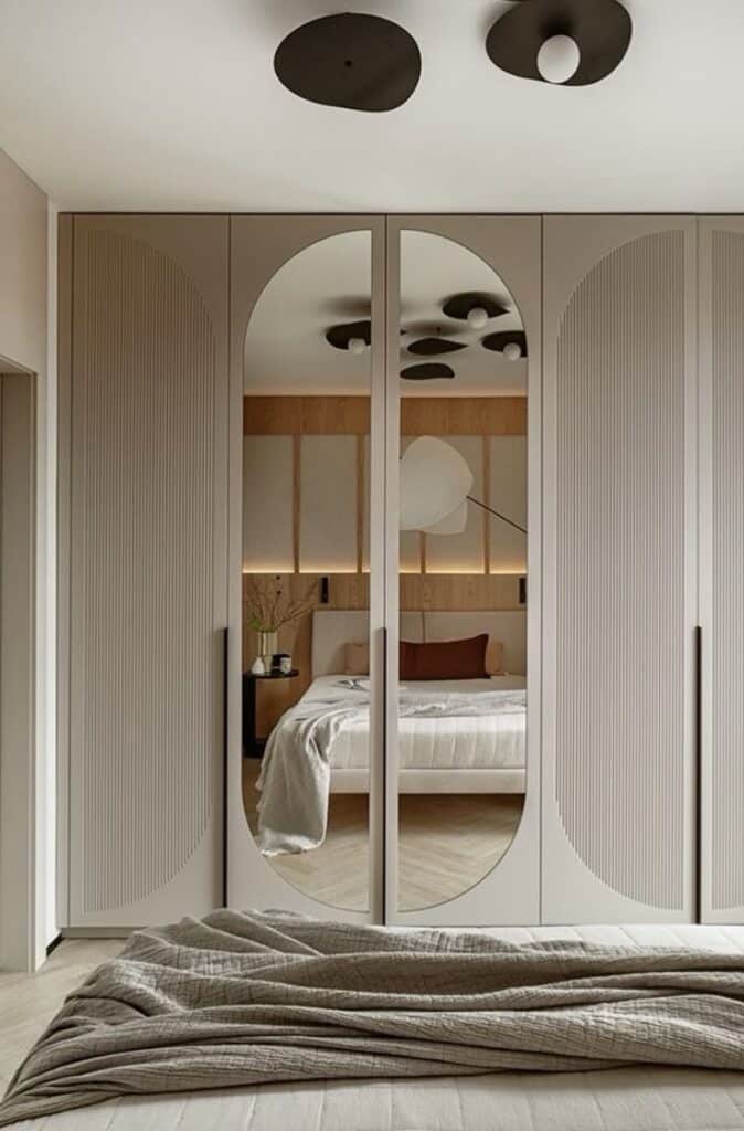 8e634b03-e6f3-45de-aa84-863195cb5769 Modern bedroom with mirrored wardrobe doors, stylish ceiling lights, and elegantly made bed. Minimalist decor. | Sky Rye Design Modern bedroom with mirrored wardrobe doors, stylish ceiling lights, and elegantly made bed. Minimalist decor.