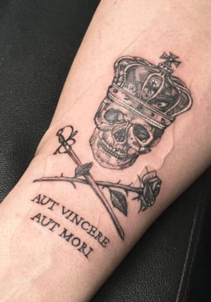 _ 9 Tattoo of a crowned skull with a sword and rose, featuring the Latin phrase Aut Vincere Aut Mori. | Sky Rye Design Tattoo of a crowned skull with a sword and rose, featuring the Latin phrase Aut Vincere Aut Mori.