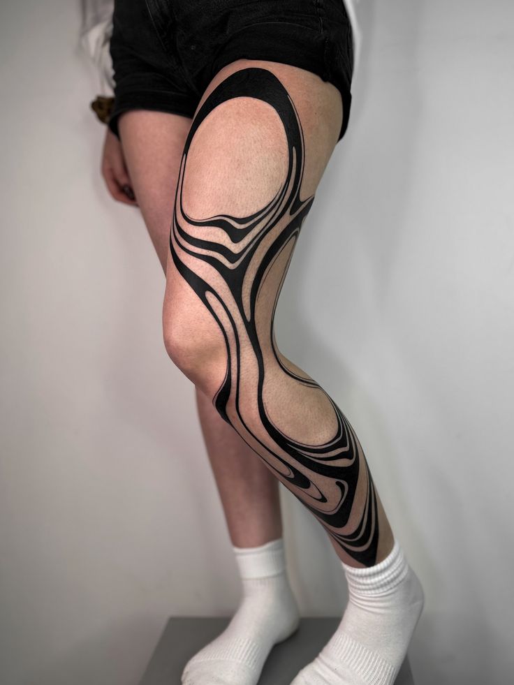 _ 9 Abstract black ink tattoo design on leg with flowing lines, showcasing artistic body art on skin, wearing white socks. | Sky Rye Design Abstract black ink tattoo design on leg with flowing lines, showcasing artistic body art on skin, wearing white socks.