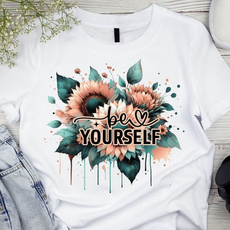 91c1538c-1e21-472b-bfcc-071d6755d234 White T-shirt with sunflower and leaf design, featuring be yourself text in bold and artistic style. | Sky Rye Design White T-shirt with sunflower and leaf design, featuring be yourself text in bold and artistic style.