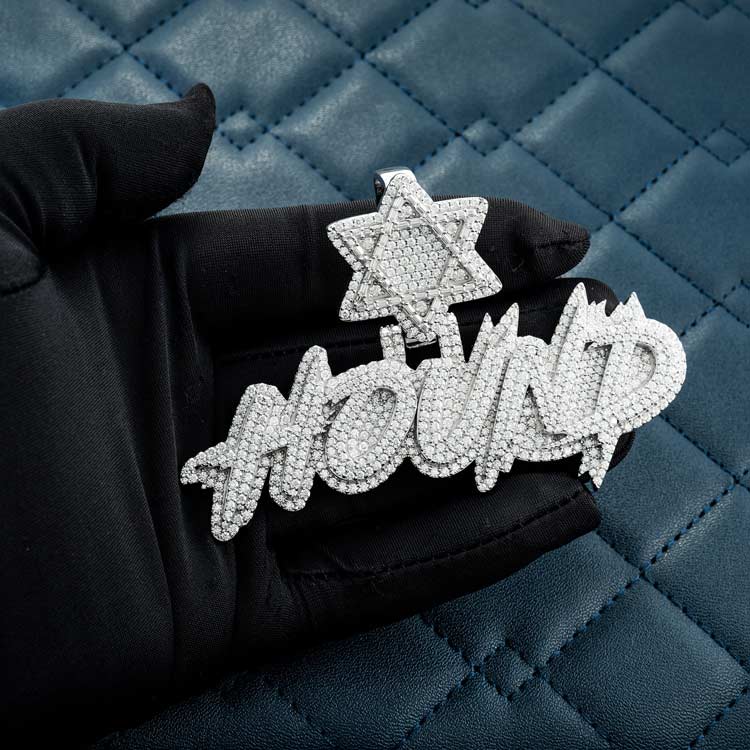 Luxury diamond-studded pendant with star design on black gloved hand, quilted blue background.