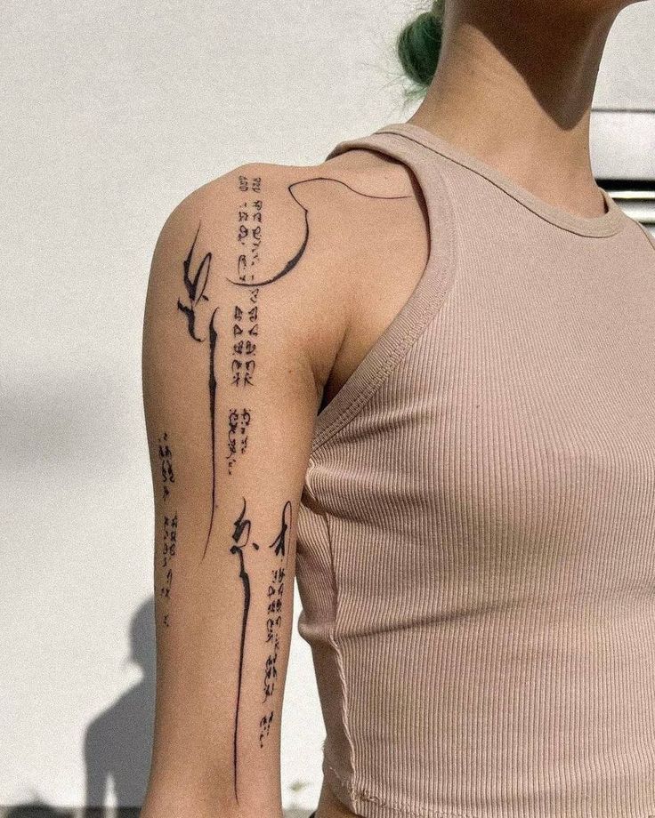 947cf026-d258-4cc4-aef7-0e1e55a68395 Person in a beige tank top showing intricate black tattoos on the upper arm. | Sky Rye Design Person in a beige tank top showing intricate black tattoos on the upper arm.